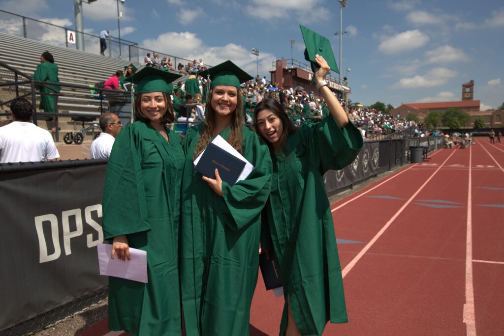 Three Emily Griffith graduates pose with their certificates at All-City Stadium