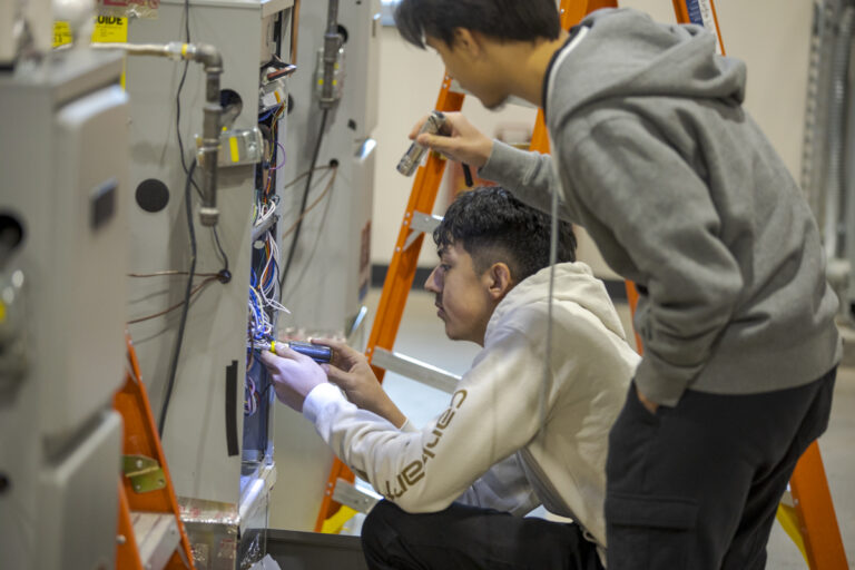 Two Male HVAC Students Look at Wiring with Flashlight in Denver, CO