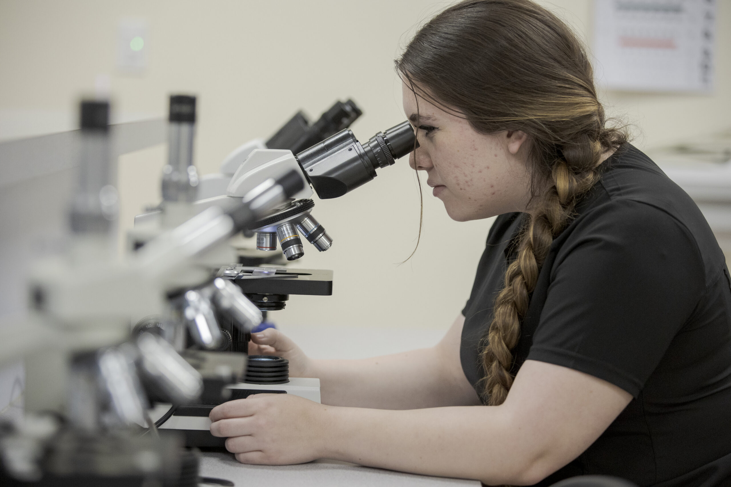 Nurse Assisting student looking into microscope in Denver, CO