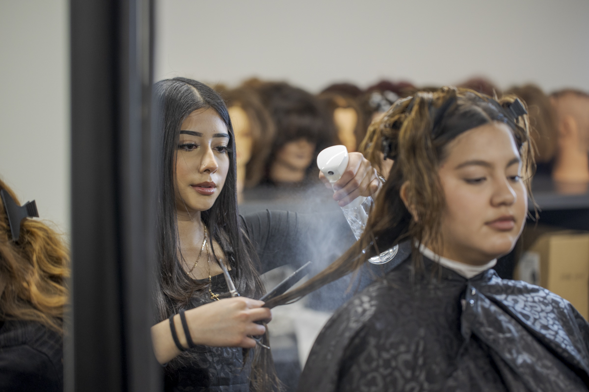 Female Cosmetology Student Spraying Water on Client's Hair in Denver, CO