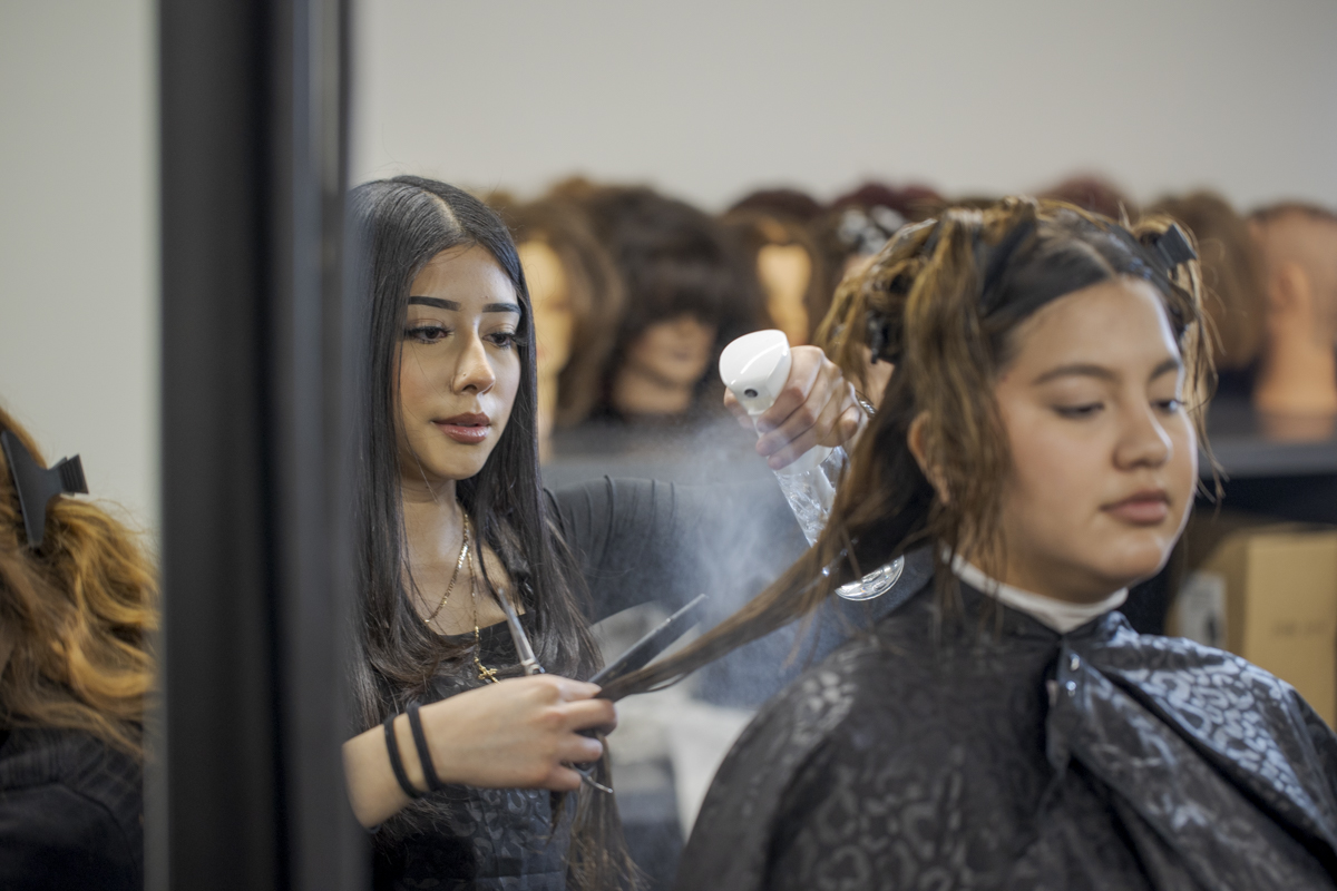 Cosmetology Student Spraying Water on Client's Hair in Denver, CO