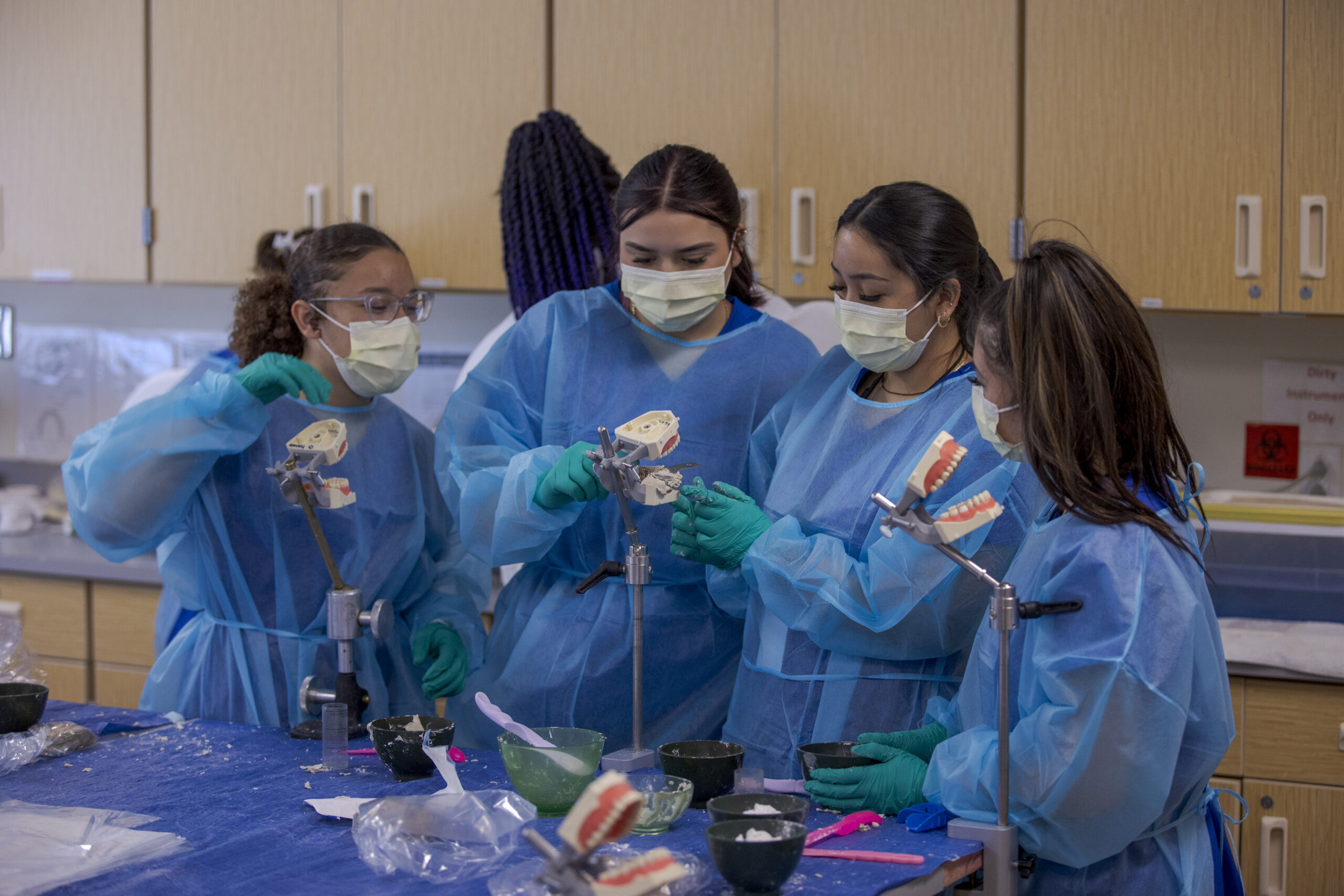 Four Dental Assisting students using practice teeth molds in Denver, CO