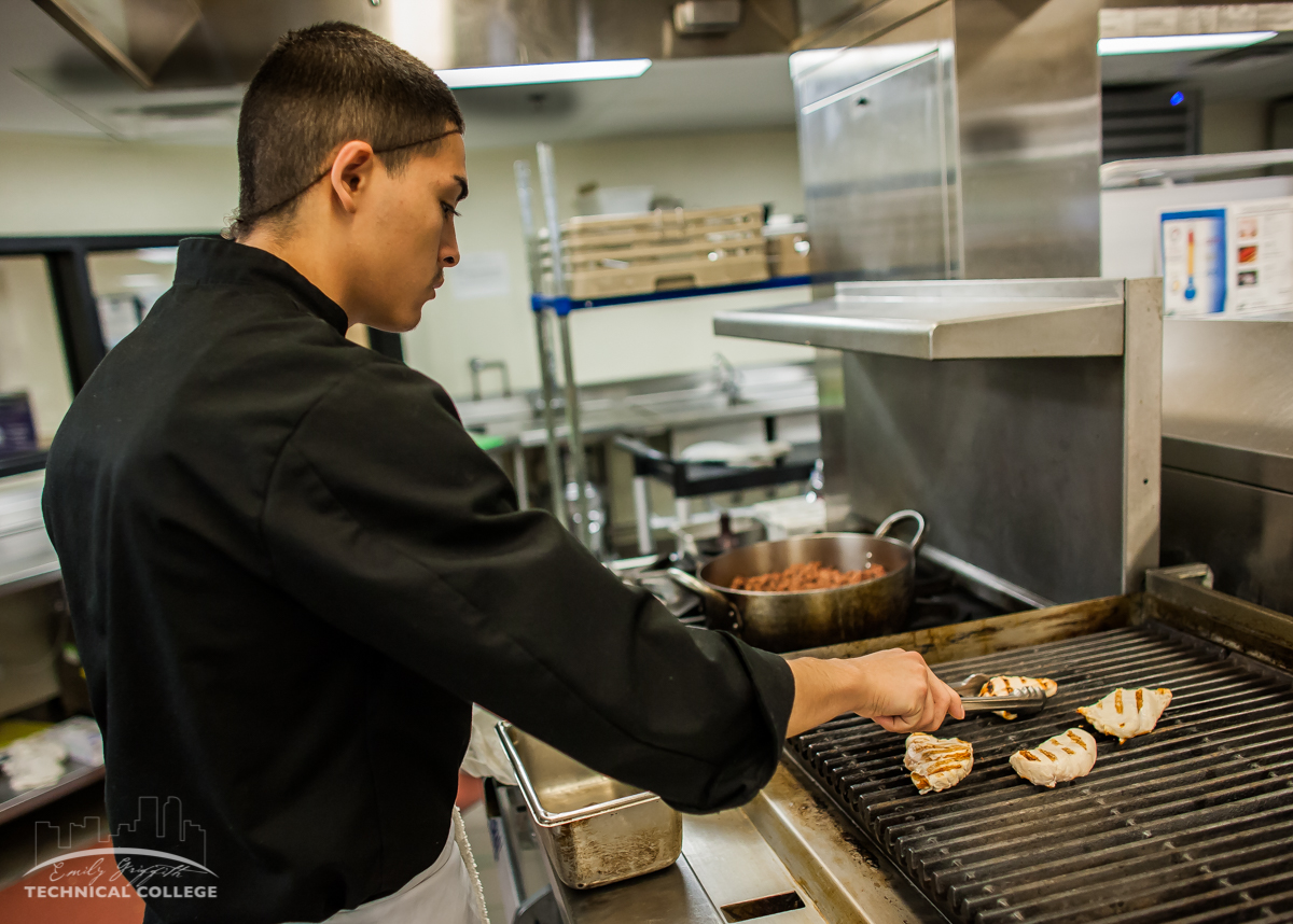 Male Culinary Arts Student Grilling Chicken on Kitchen Grill in Denver, CO