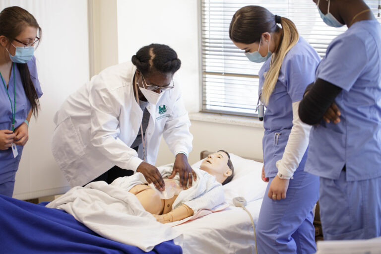 Nurse Assistant instructor demonstrates techniques for students on mannequin in Denver, CO