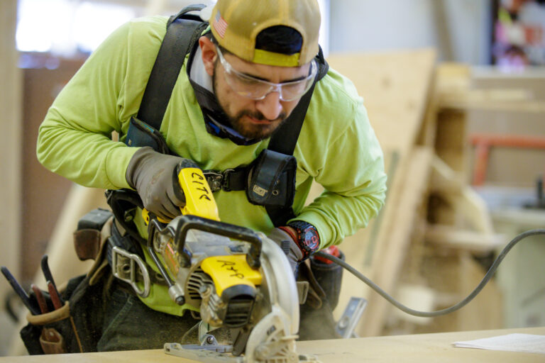 Apprenticeship student using circular saw to cut a piece of wood