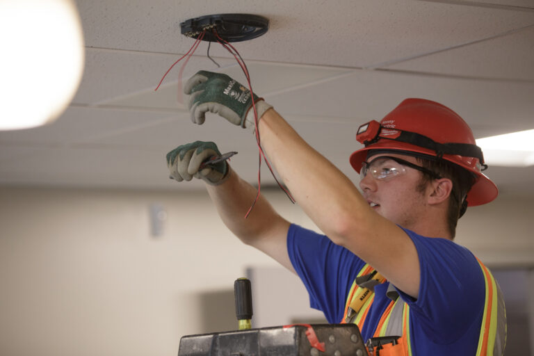 Electrical Apprenticeship student clips wires hanging from ceiling