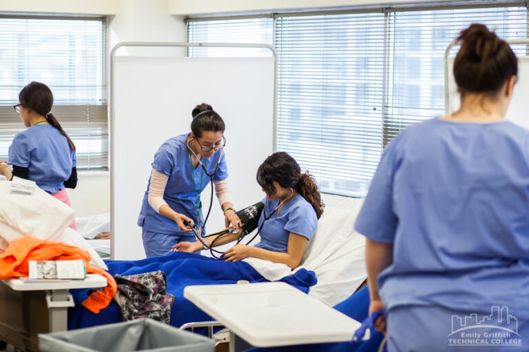 Nurse Assistant students practice using stethoscope and blood pressure cuff in Denver, CO