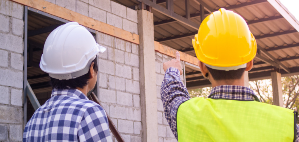 Construction workers wearing helmets observing building