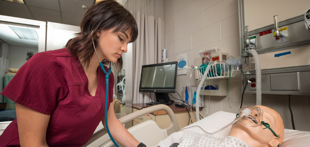 Nursing student using stethoscope on mannequin patient