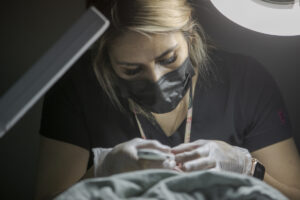 Esthetician student looking downward and observing client's face underneath a lamp