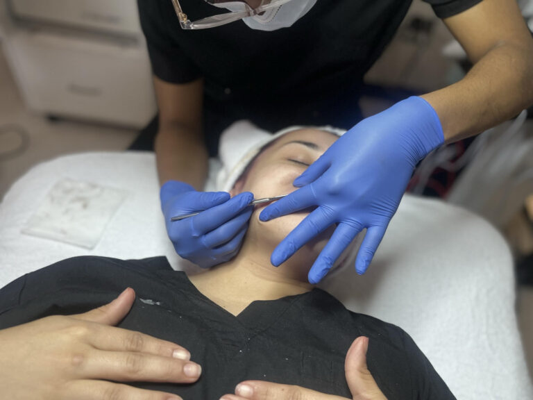 Esthetician student dermaplaning a client's face