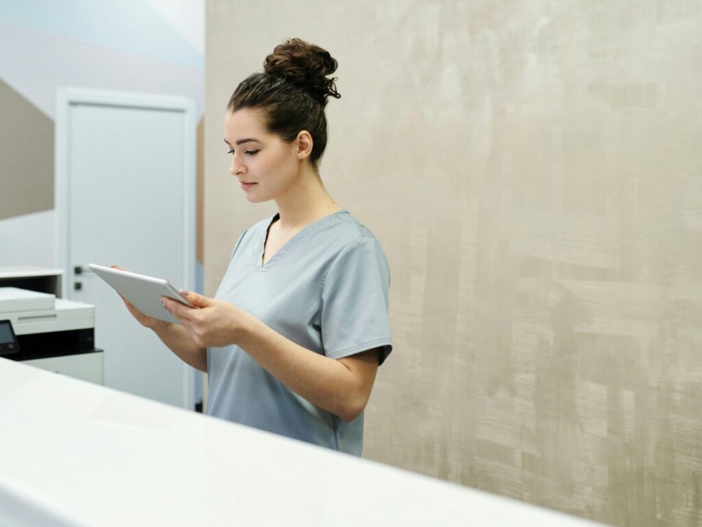 Professional receptionist in uniform using a tablet in a modern office setting.