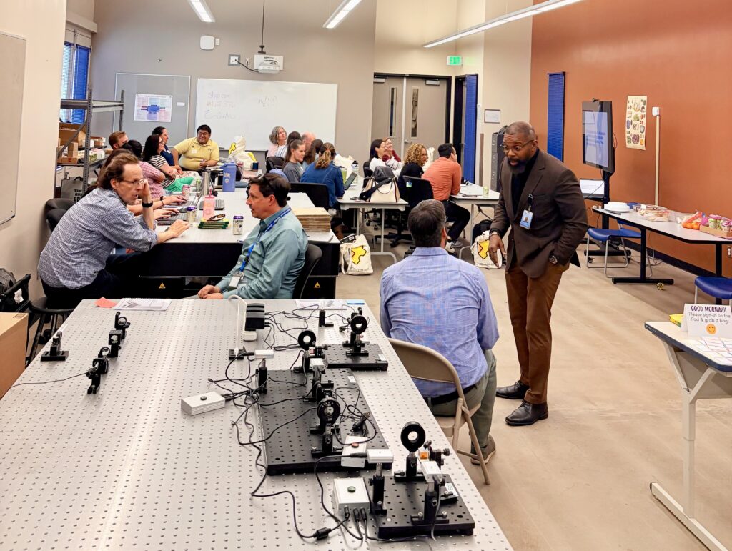 Participants in QCaMP—a professional development program introducing K-12 educators to quantum information science—at Emily Griffith Technical College’s Osage campus. Dr. Charles Tahan (standing, right) leads the session, while Dr. Boaz Nash (seated, second from left) will head the college’s upcoming Quantum Technician program.