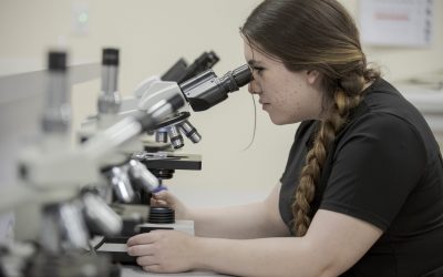 Nurse Assisting student looking into microscope in Denver, CO