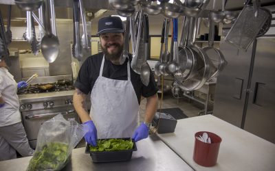 Smiling Culinary Arts student food prepping in industrial kitchen